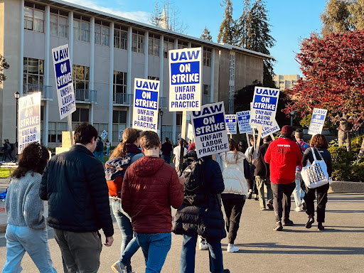 UC workers holding up signs calling for unfair labor practices